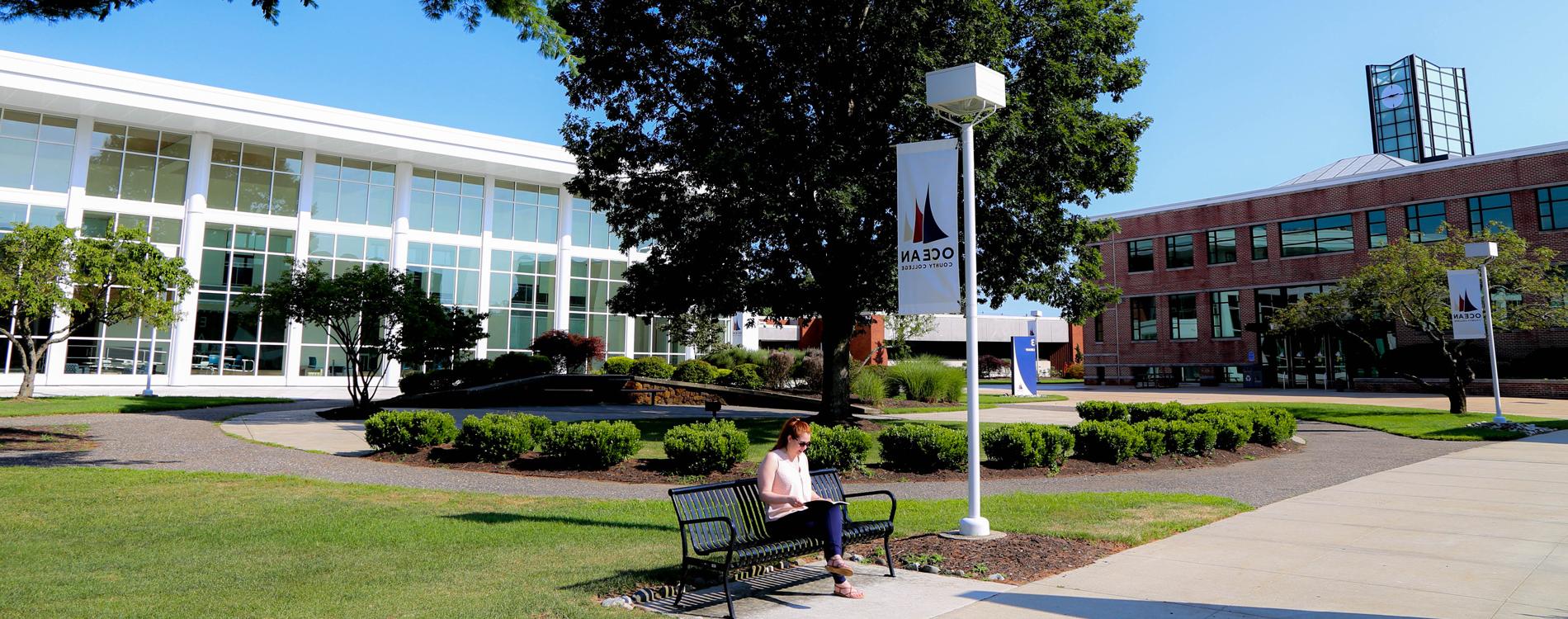 student sitting on bench in front of the instructional building